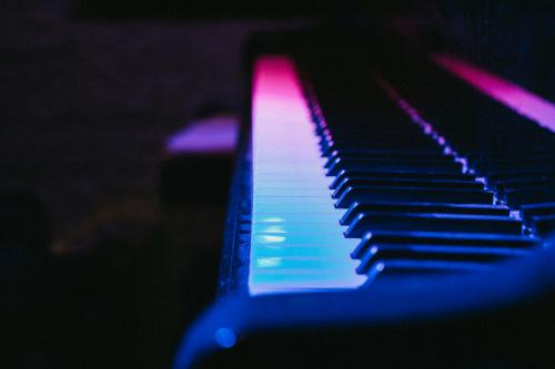 Piano keys under blue and magenta lights.